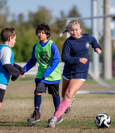 Young soccer players in practice vests high-fiving and interacting positively during a team training session.