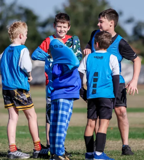 A group of young male soccer players huddled together and laughing during a break, showing the fun community atmosphere of the club.